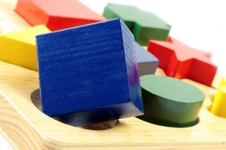 Square peg in a round hole. Wooden block shapes, with square block over round hole. Please see also: