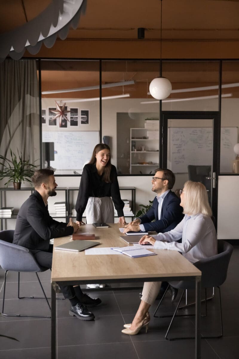 A team laughing as they work together with their leader. CREDIT: https://www.istockphoto.com/portfolio/fizkes